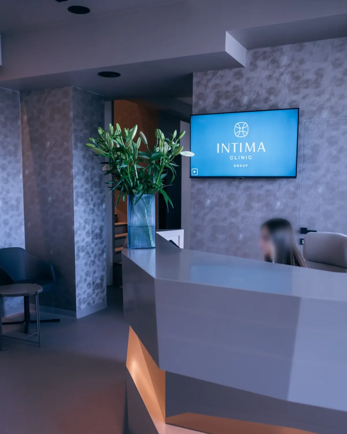 Ekran z logo Intima nad recepcją kliniki