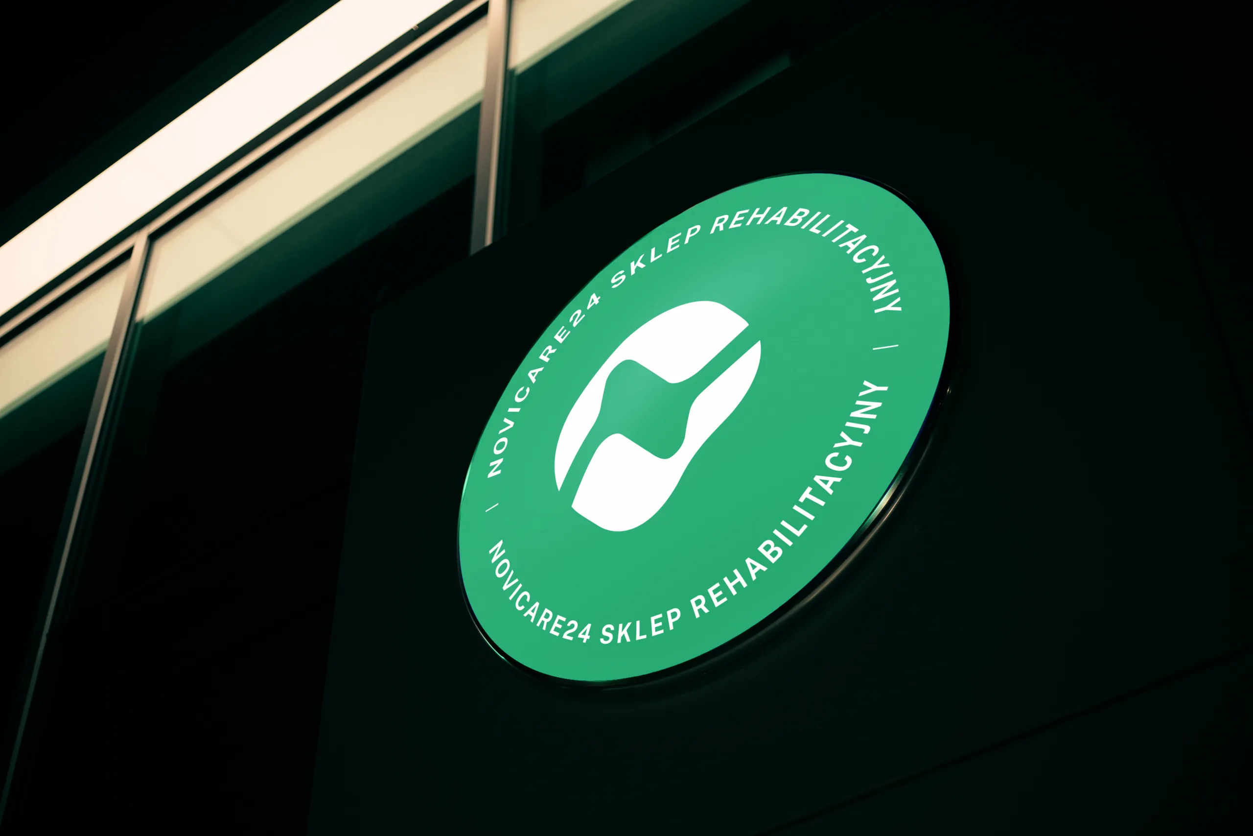 Zielony okrągły szyld Novicare24 z napisem Sklep rehabilitacyjny