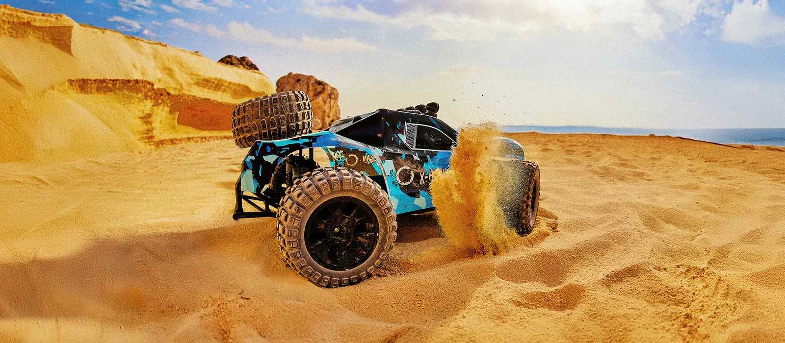Niebieski short course truck w kurzu na plaży
