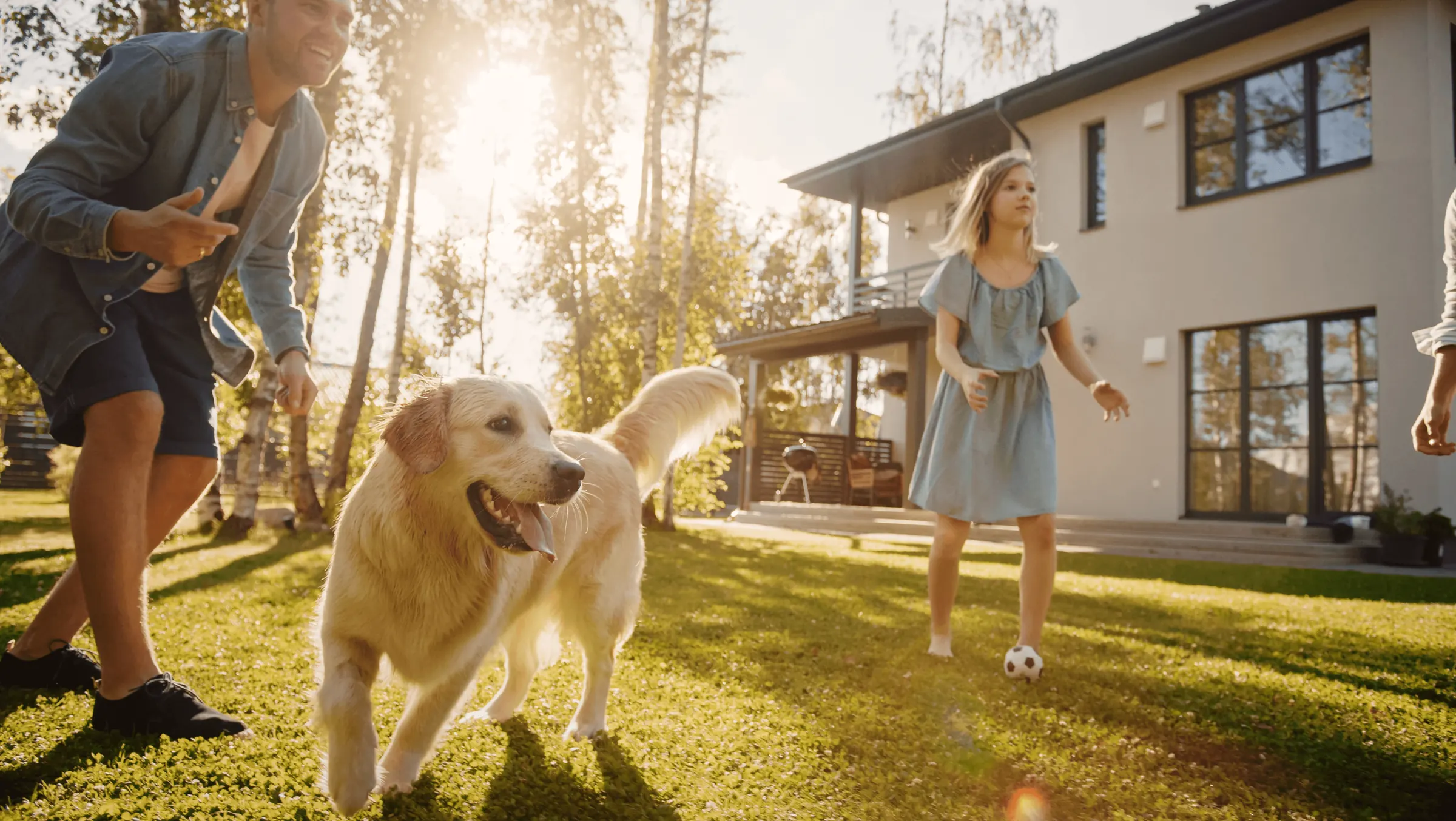 Rodzina bawi się z golden retrieverem w ogrodzie przed domem