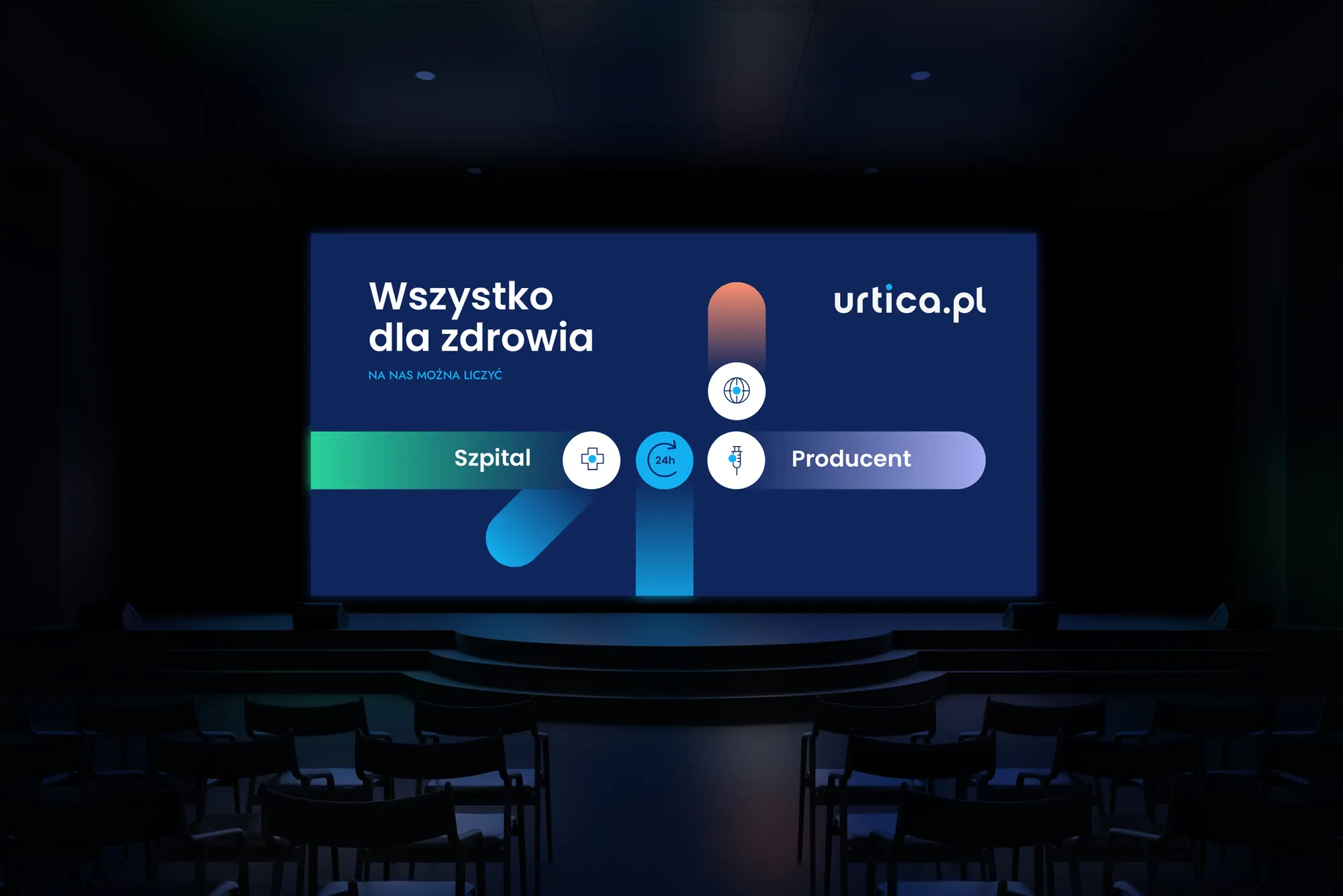 Ekran w ciemnej sali konferencyjnej z hasłem „Wszystko dla zdrowia” i grafiką Szpital – Producent z kropką pośrodku.