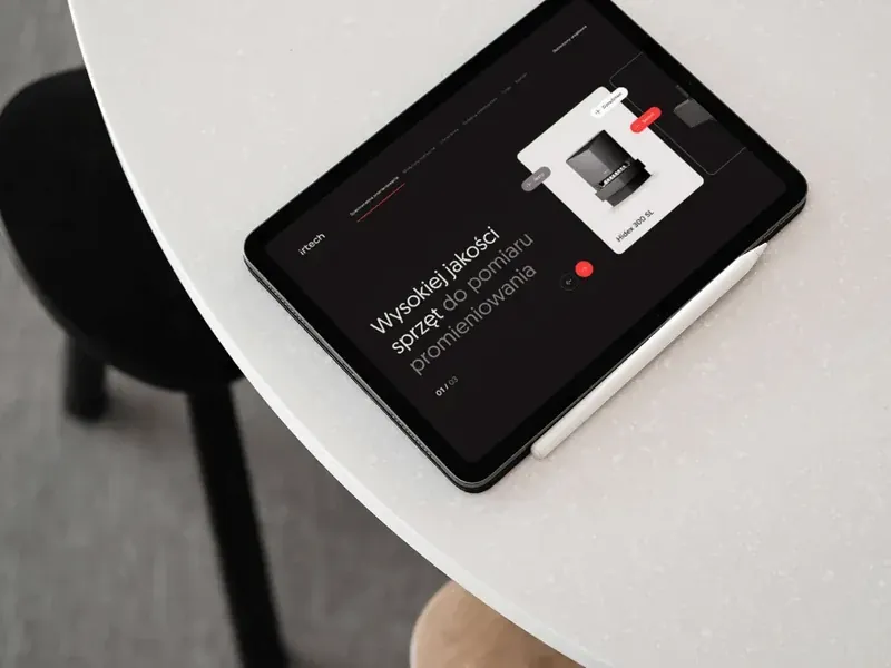 Tablet na okrągłym stoliku ze stroną irtech: hasło o sprzęcie do pomiaru promieniowania i zdjęcie urządzenia.